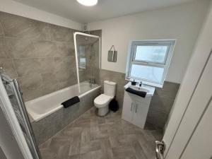 a bathroom with a toilet and a tub and a sink at Brand new refurb 8 person house in Hull