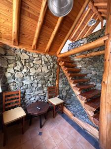 an attic with two chairs and a stone wall at Los Retoños in El Bolsón