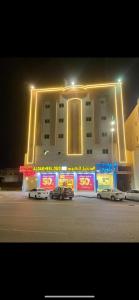 شقق نجوم الجزيرة للشقق المخدومة في تبوك: مبنى فيه سيارات تقف امامه ليلا