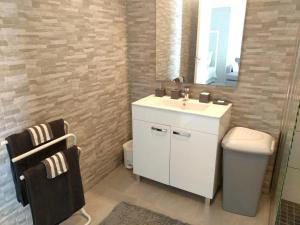 een badkamer met een witte wastafel en een spiegel bij Studio avec vue sur la mer terrasse amenagee et wifi a Le Robert in Le Robert