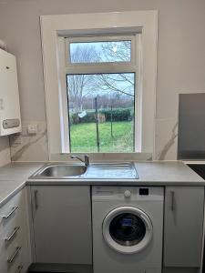een keuken met een wastafel en een wasmachine bij Urban Oasis:perfect stay in city in Edinburgh