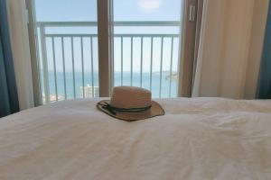 a hat sitting on top of a bed with a window at Ocean view the latest home appliance built in in Tu-dong