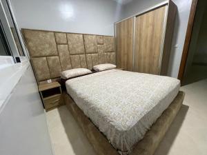 Schlafzimmer mit einem großen Bett mit einem gepolsterten Kopfteil in der Unterkunft Jada Gzenaya in Tangier