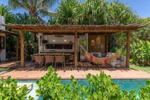 Casa con terraza de madera con mesa y sillas en Nossa Villa Caraíva, en Caraíva