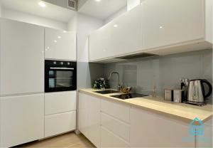 una cocina blanca con armarios blancos y fregadero en White Apartment, en Gdansk