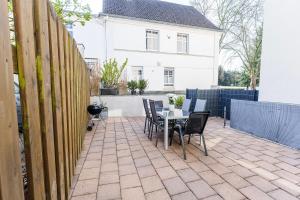 a patio with a table and chairs and a white house at Große Terassen-Wohnung mit Grill, Playstation 5, Billardtisch und Massagesessel in Haan