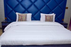 a large white bed with a blue head board at The Royal Sea Clifton in Karachi