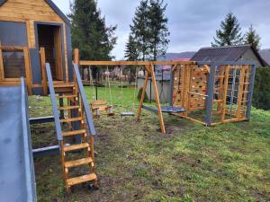 a wooden playground with a ladder and a house at Guzikowa Chata in Dobczyce