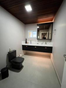 a bathroom with a toilet and a large mirror at Casa de Campo - Rancho dos Lagos in Cascavel