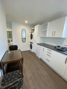 uma cozinha com armários brancos, uma mesa e uma cadeira em Birch Court - Tui em Whanganui