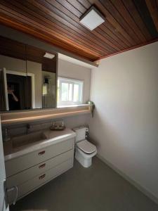 a bathroom with a toilet and a sink and a mirror at Casa de Campo - Rancho dos Lagos in Cascavel