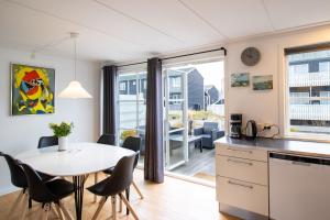 kuchnia i jadalnia ze stołem i krzesłami w obiekcie Hyggelig sommerhus Øer Maritime ferieby Ebeltoft w mieście Ebeltoft