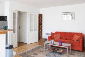een woonkamer met een rode bank en een tafel bij Bright and quiet apartment with unobstructed view in Boulogne-Billancourt