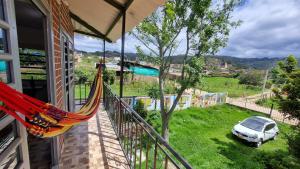 a balcony with a hammock and a car parked on the grass at Vivienda Rural La Estancia in Duitama