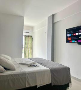 una camera da letto con un letto e una tv a parete di Hotel New Tokyo a Capitão Poço