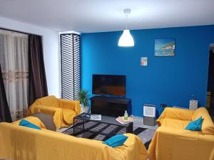 a living room with two yellow chairs and a blue wall at Down town house with uni sence! in Athens