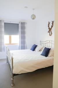 a white bedroom with a large bed with blue pillows at Number1Townhouse with private balcony & Parking in Glasgow