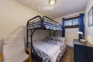 - une chambre avec des lits superposés, une chaise et un bureau dans l'établissement Au chalereux chalet Petite-rivière-saint-françois, à Petite-Rivière-Saint-François