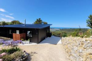 a black house with a stone wall at Golden Bay Heights - Luxury Accommodation in Parapara 