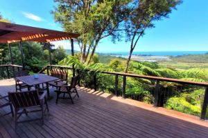 a wooden deck with a table and chairs on it at Golden Bay Heights - Luxury Accommodation in Parapara 