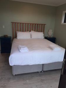 a bed with white sheets and two towels on it at Golden Bay Heights - Luxury Accommodation in Parapara 