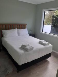 a bedroom with a bed with two towels on it at Golden Bay Heights - Luxury Accommodation in Parapara 