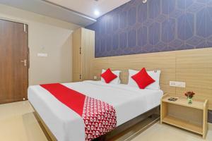 una camera da letto con un grande letto bianco con cuscini rossi di The Botanica Grand a Kondapur