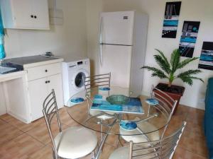 una cucina con tavolo in vetro, sedie e frigorifero di The Cupid Chalet a Belmont