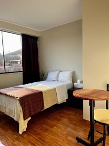 een slaapkamer met een bed, een tafel en een raam bij COSMOPOLITAN INN in Ventanilla