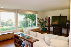 a living room with a white couch and a flat screen tv at Best Ocean & Bay Views in SD Large Backyard Air Conditioning in San Diego