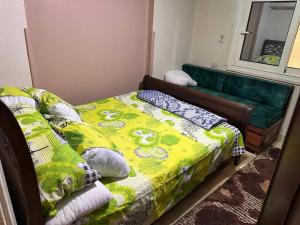een slaapkamer met een bed en een groene bank bij Bienvenidodepartamento in Caïro