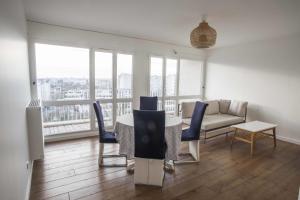 sala de estar con mesa, sillas y sofá en Charming 63 m2 apt with views of the Eiffel Tower, en LʼÎle-Saint-Denis