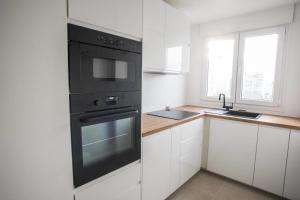 cocina con horno negro y fregadero en Charming 63 m2 apt with views of the Eiffel Tower, en LʼÎle-Saint-Denis