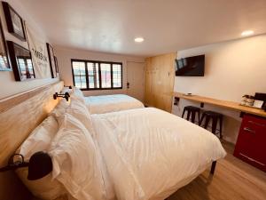 een slaapkamer met 2 witte bedden en een bureau bij The Timberline in Leadville
