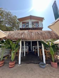 a house with a straw roof with tables and chairs at Cristal Blue Barú in Baru