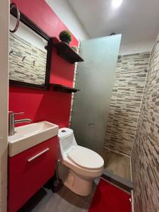 a bathroom with a toilet and a red wall at La Puerta Blanca #5 in Puerto Vallarta