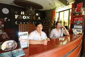dos personas sentadas en un mostrador en una tienda en Hotel Frontera, en Tacna
