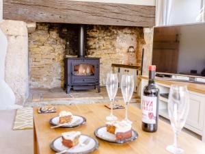 a table with wine glasses and cake and a fireplace at 3 Bed in Bourton-on-the-Water PTREE in Bourton on the Water