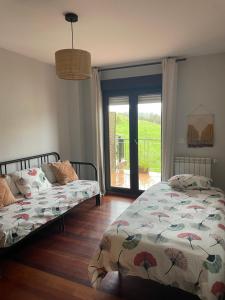 a bedroom with two beds and a sliding glass door at LA TERRAZA in Comillas
