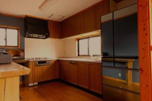a kitchen with wooden cabinets and a black refrigerator at WAKURABA- Chalet with the best views in Hakuba! in Hakuba