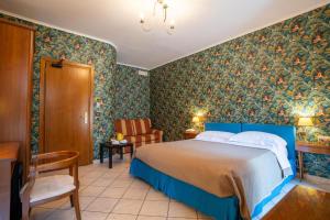 a bedroom with a blue bed and floral wallpaper at Locanda Da Otello in Marta