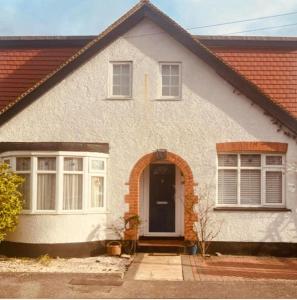 una casa bianca con porta e finestre di Gorgeous Cosy home 2 Miles from Heathrow Airport ad Ashford