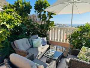 une terrasse avec un canapé, des chaises et un parasol dans l'établissement Los Gigantes Buenavista Ocean View Apartment, à Acantilado de los Gigantes