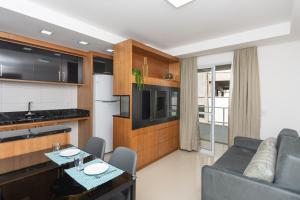 uma cozinha e sala de estar com um sofá e uma mesa em Apto 750m da UFSC, Sacada com Churrasqueira e Academia FU3431 em Florianópolis