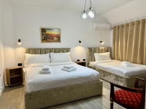 a bedroom with two beds and a chair at VILA ALIZEE Hotel in Tirana