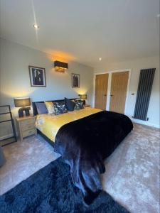 een slaapkamer met een groot bed en een zwarte deken bij Bumblebee Barn, Luxury contemporary holiday home in Perranporth
