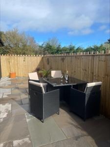 een patio met stoelen, een tafel en een hek bij Bumblebee Barn, Luxury contemporary holiday home in Perranporth