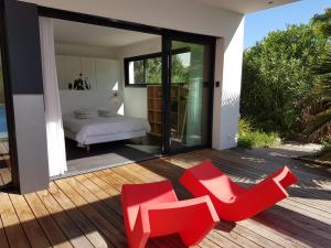 een slaapkamer met een bed en rode stoelen op een terras bij Villa CALIFORNIA Piscine chauffée 14x4m Abatilles Mouleau 10 pers in Arcachon