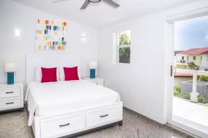 a white bedroom with a white bed and a window at 247C South Finger in Jolly Harbour