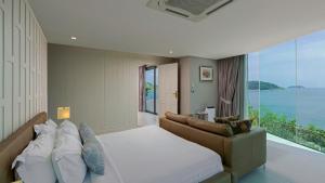 a bedroom with a bed and a couch and a window at Villa Thousand Cliffs in Nai Harn Beach